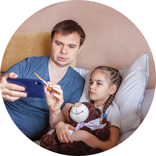 A father with his sick daughter, showing a thermometer to a virtual care call on his cellphone 